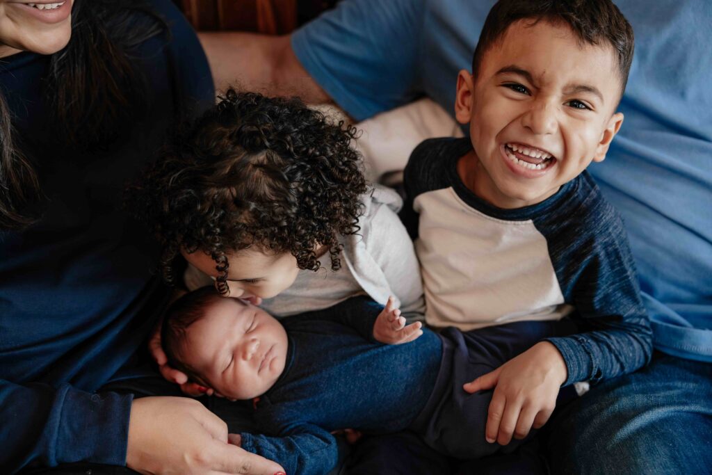 Big and Brother sister snuggling newborn in Elmhurst IL by Taylor Lynn Studios