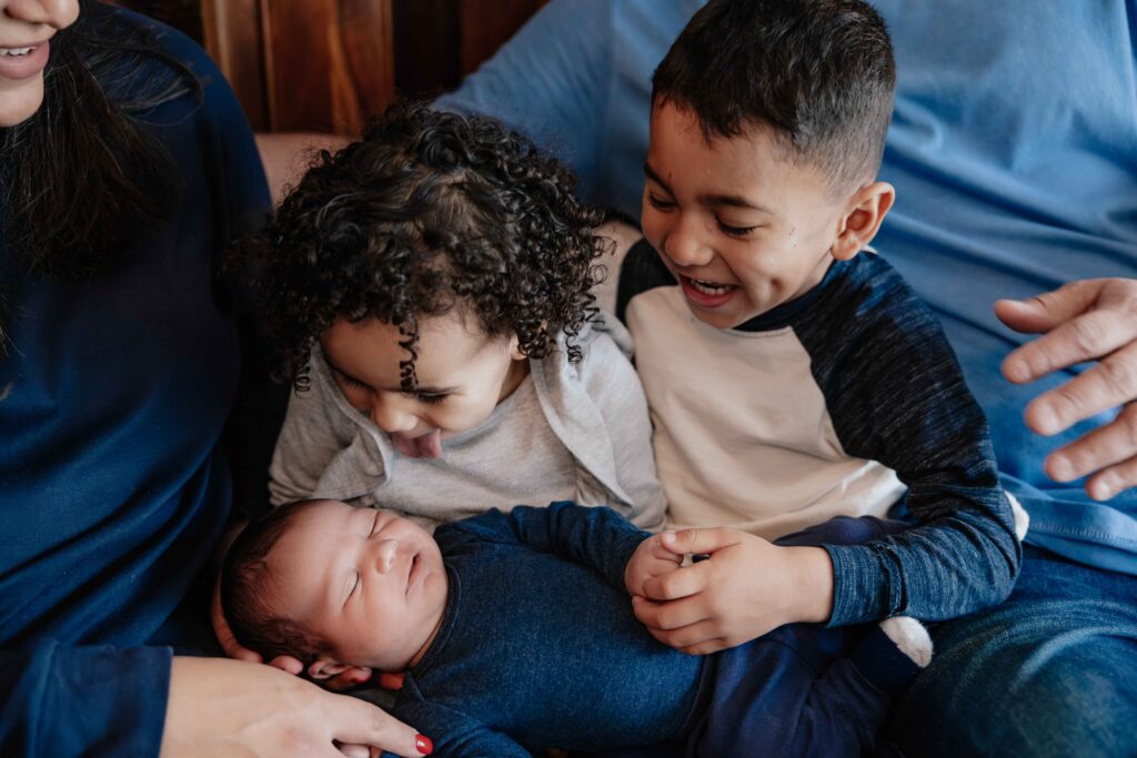 Older siblings snuggling newborn in Elmhurst IL by Taylor Lynn Studios