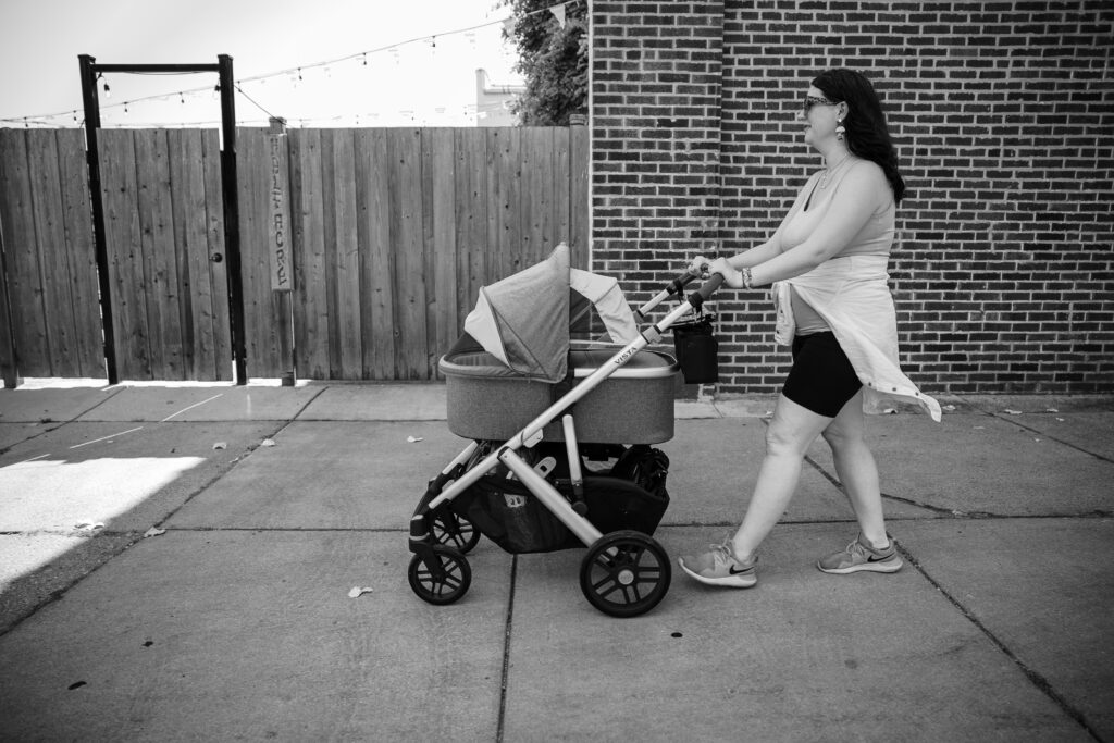 Postpartum mom pushing a stroller along the sidewalk near family friendly park in Ravenswood, Chicago.